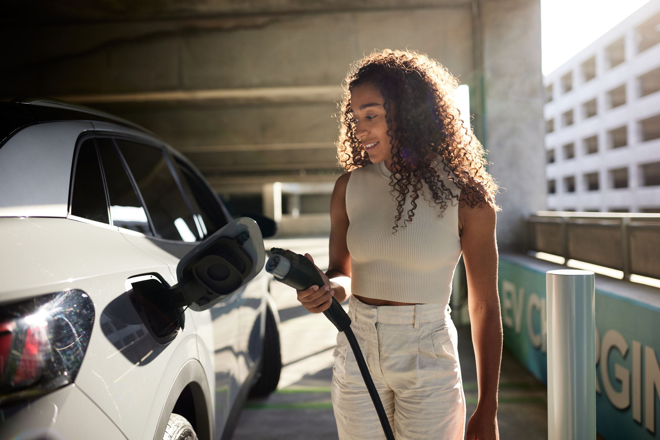 Mulher abastece carro elétrico